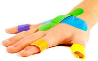 A picture of a Childs hand with multiple colourful plasters on