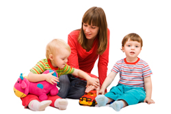 A picture of a Mother playing with her two children using blocks